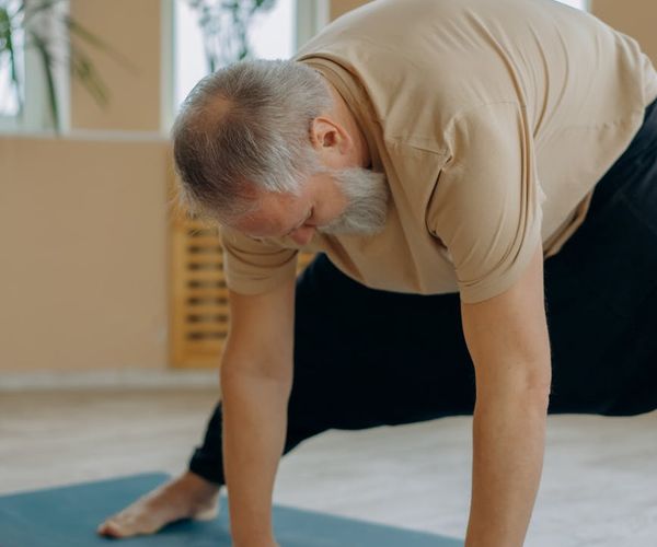 Man stretching hamstrings in a forward fold yoga pose.